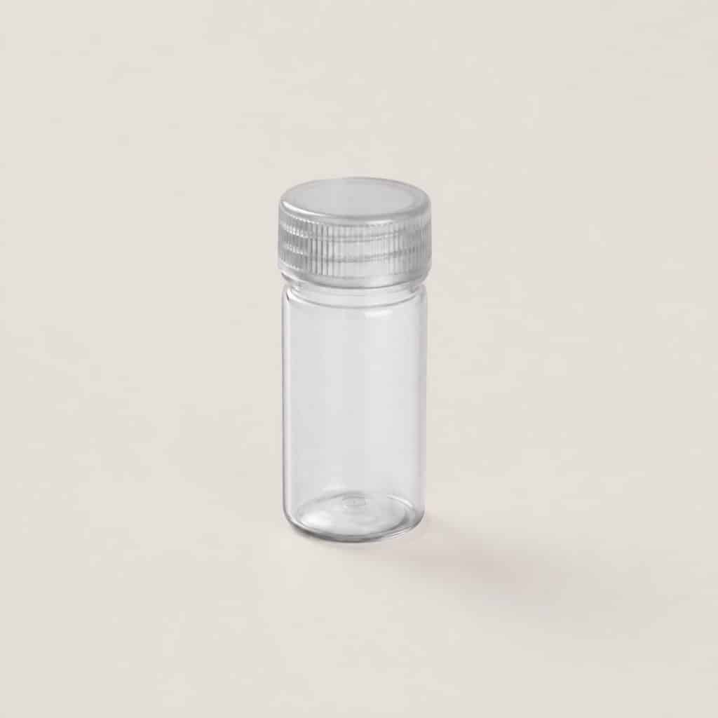Pilulier doseur transparent pour granules, posé seul sur fond clair